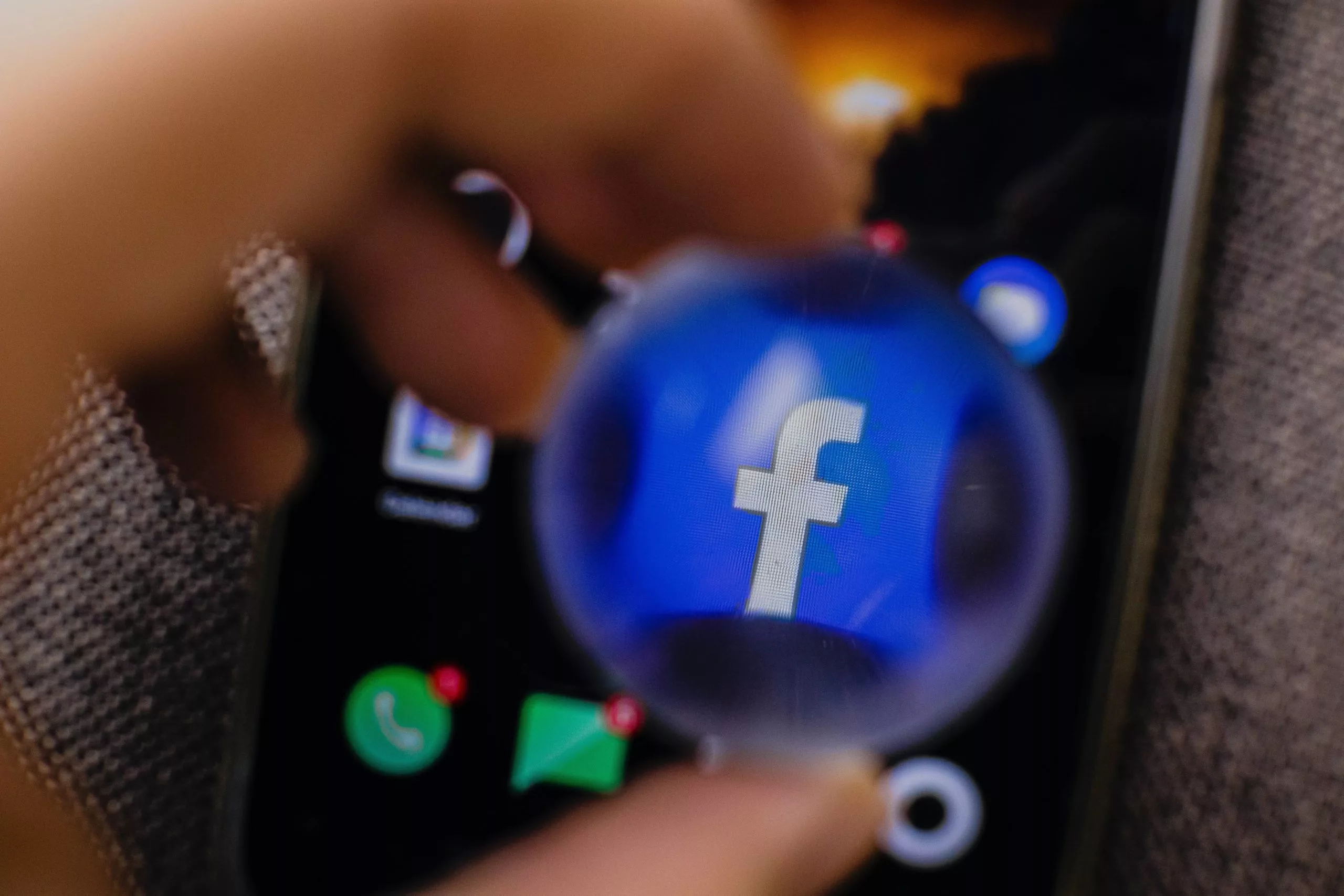A Facebook iPhone app icon magnified through a handheld lens
