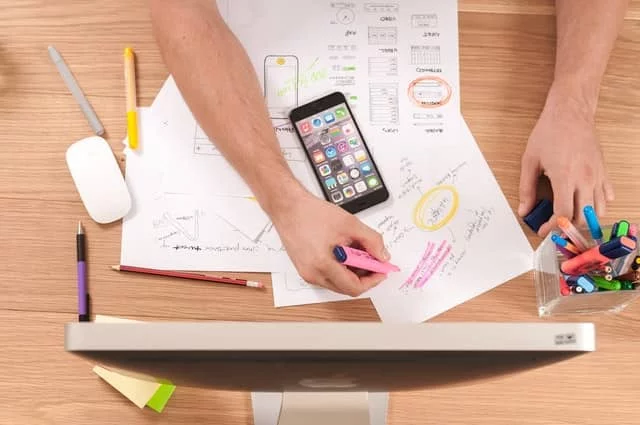 notes and a smart phone in front of a computer
