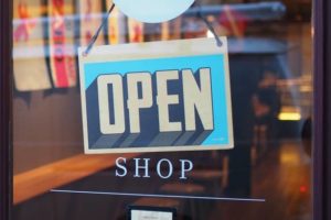 Close-up of a brick-and-mortar shop front window with an “Open” sign displayed