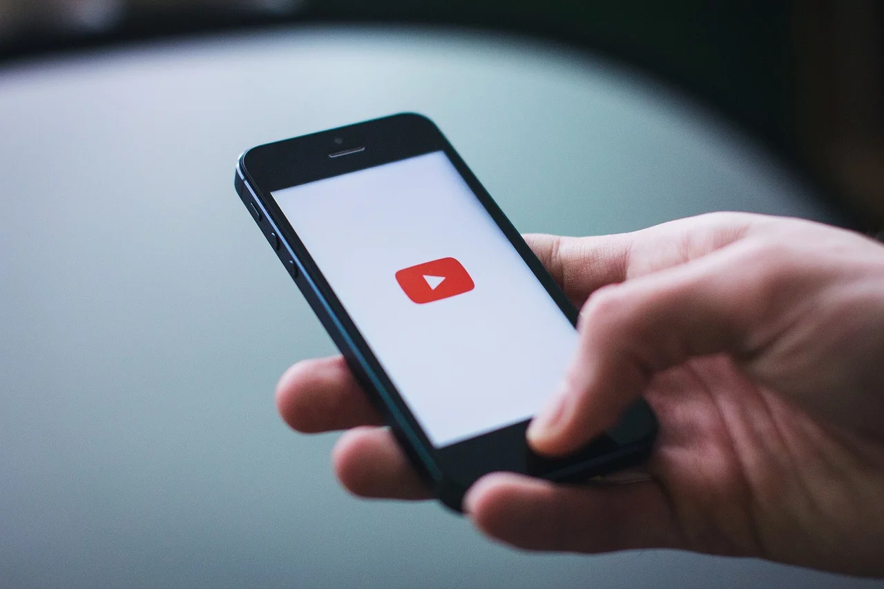 Close-up of someone holding a mobile phone wit]h the YouTube video app displayed