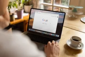 A person sitting in front of a laptop with the Google browser pulled up